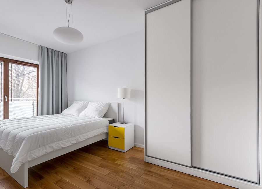 Contemporary bedroom featuring sleek white sliding wardrobe doors, expertly crafted to fit the space perfectly for a polished and modern look.